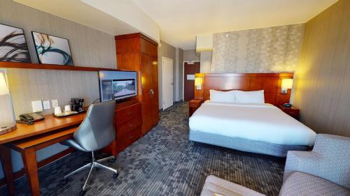a hotel room with a bed and a desk and a computer at Courtyard by Marriott Dallas Allen at Allen Event Center in Allen