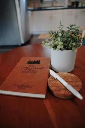 a book on a table next to a potted plant at Creek Side Cabin with Wood Fired Hot Tub and Fire Pit in New Milford