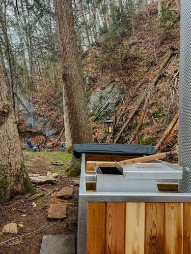 a wooden structure with a stove in the woods at Creek Side Cabin with Wood Fired Hot Tub and Fire Pit in New Milford