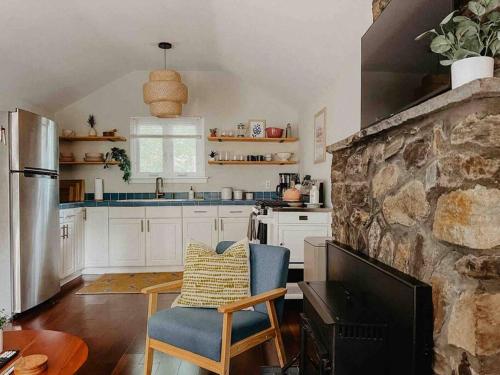 a kitchen with white cabinets and a stone wall at Creek Side Cabin with Wood Fired Hot Tub and Fire Pit in New Milford