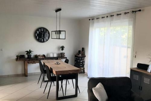 une salle à manger avec une table et une horloge au mur dans l'établissement Maison, à Lombez