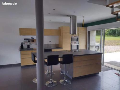 une cuisine avec deux tabourets de bar et un comptoir dans l'établissement Gite de saint Antoine, à Ploudiry