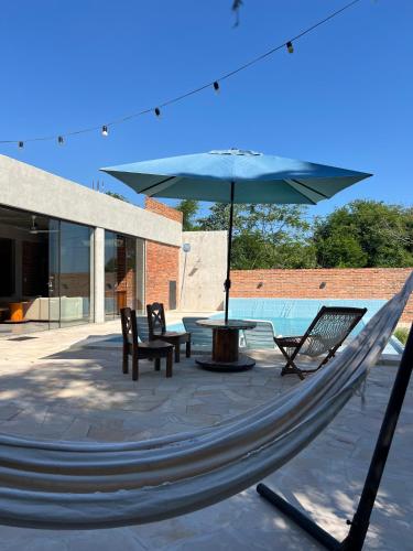 a hammock with chairs and a table and an umbrella at Casa de verano en San Bernardino in San Bernardino