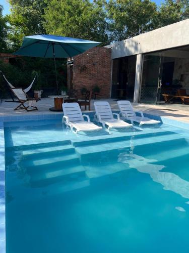 a group of chairs and an umbrella in a swimming pool at Casa de verano en San Bernardino in San Bernardino