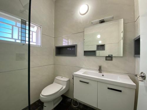 a white bathroom with a toilet and a sink at Town House isla de margarita in La Sabana