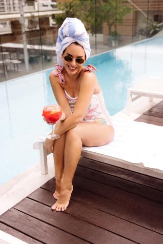 a woman sitting next to a pool holding a drink at Kimpton Margot Sydney by IHG in Sydney