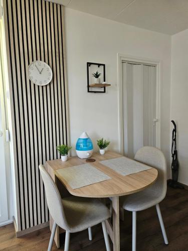 a dining room table with chairs and a clock on a wall at Modern Apartment S22 in Niš