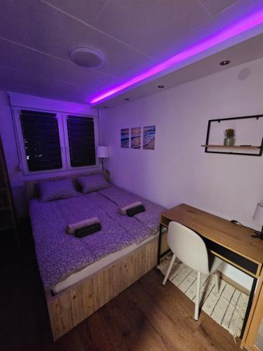 a bedroom with a bed and a desk and purple lights at Modern Apartment S22 in Niš