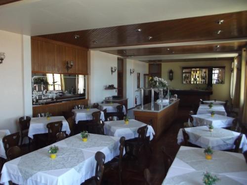 um restaurante com mesas e cadeiras brancas e um balcão em Hotel San Carlos em Carlos Barbosa
