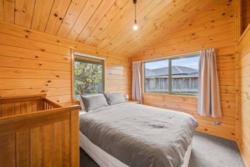 a bedroom with a bed in a wooden cabin at Family Stays very private close to Park with a Games Room Sleeps 10 in Wanaka