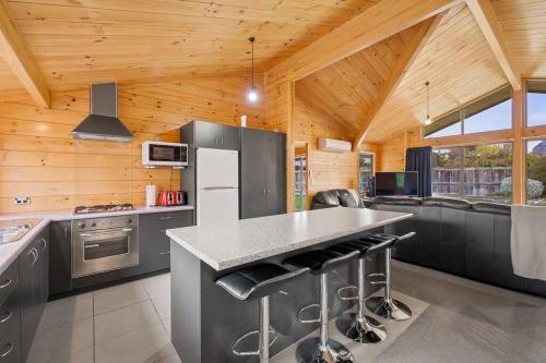 a kitchen with stainless steel appliances and a wooden ceiling at Family Stays very private close to Park with a Games Room Sleeps 10 in Wanaka