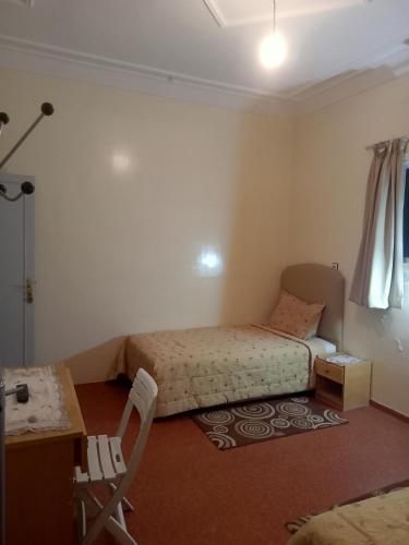 a bedroom with two beds and a table and a desk at Maison d'hôtes afoulki tafraout in Tafraoute