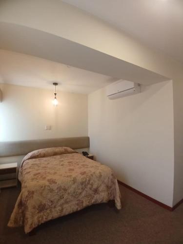 a bedroom with a bed and a white wall at Hotel Melodia in Lima