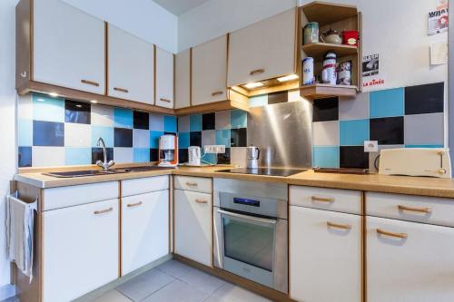 - une cuisine avec des placards blancs et du carrelage bleu et blanc dans l'établissement Appartement lumineux et cosy Strasbourg, à Strasbourg