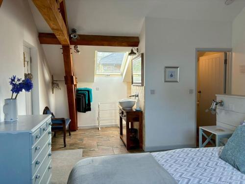 a bedroom with a bed and a dresser and a bathroom at Little Bream - pretty cosy cottage, sea views, walk to the beach in Mawnan Smith