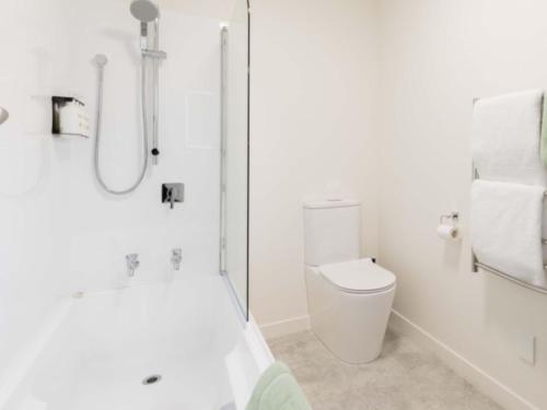 a white bathroom with a shower and a toilet at The Milano Christchurch in Christchurch