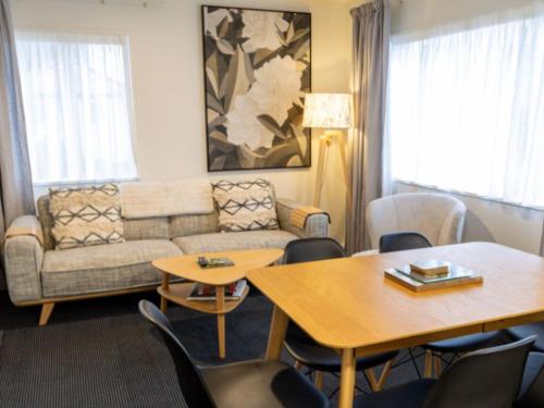 a living room with a couch and tables and chairs at The Milano Christchurch in Christchurch
