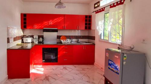 a red kitchen with red cabinets and a refrigerator at Rubis Appart Majunga in Mahajanga
