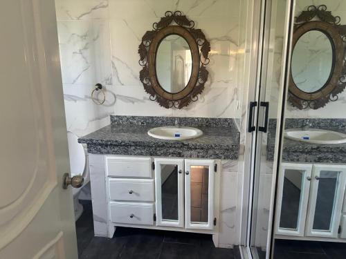 une salle de bain avec deux lavabos et deux miroirs dans l'établissement Casa las Américas, à La Alianza