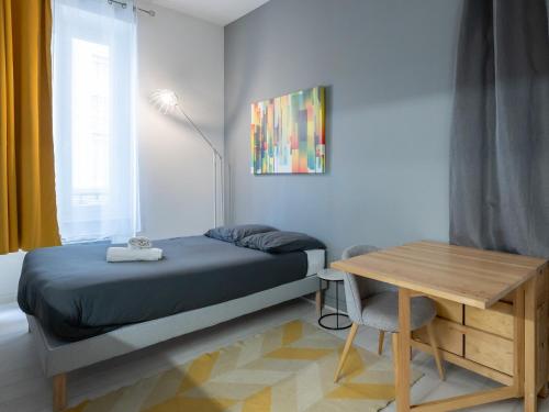 - une petite chambre avec un lit et une table en bois dans l'établissement Le Nid Lyonnais - Montchat, à Lyon