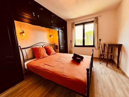 una camera da letto con un letto con lenzuola arancioni e una finestra di La Détente Provençale - Tennis, Football, Pétanque a Le Val