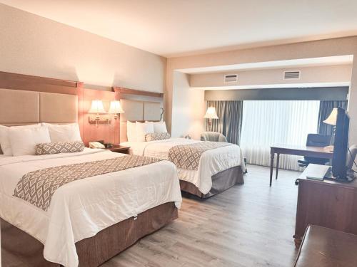 a hotel room with two beds and a flat screen tv at Clayton Plaza Hotel & Extended Stay in Clayton
