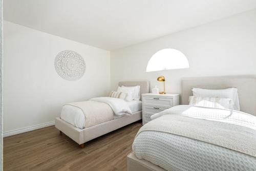 a white bedroom with two beds and a lamp at Newly Renovated Condo in Palm Desert in Palm Desert