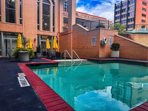 a swimming pool in front of a brick building at Clayton Plaza Hotel & Extended Stay in Clayton