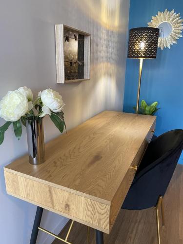 une table en bois avec un vase de fleurs et une lampe dans l'établissement Marianne 2, à Bergerac