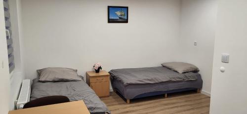 a room with two beds and a nightstand and a bed sidx sidx sidx sidx at Apartamenty Ścinawa in Ścinawa