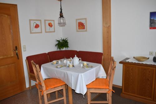 - une table à manger avec une nappe et des chaises blanches dans l'établissement Gästehaus Bergfrieden, Ferienwohnung Susanne, à Bad Bayersoien