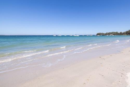 a sandy beach with boats in the water at Sails Blu, Callala Bay in Callala Bay