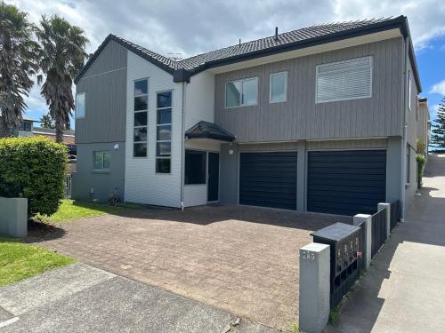 a house with a garage and a driveway at At The Bay - Mt Maunganui Holiday Home in Matapihi
