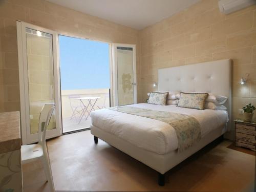 a bedroom with a large bed and a large window at GozoWindmill Apartments in Qala