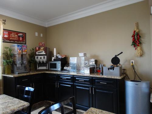 a kitchen with black cabinets and a counter top at Regency Inn & Suites - Baytown in Baytown