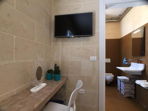 een badkamer met een toilet en een tv aan de muur bij GozoWindmill Apartments in Qala