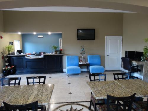 a waiting room with blue chairs and tables at Regency Inn & Suites - Baytown in Baytown