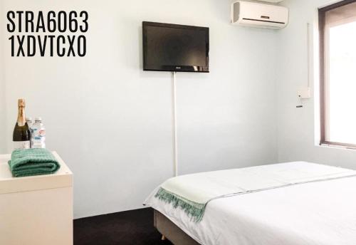 a bedroom with a bed and a tv on the wall at Caversham B&B in Perth