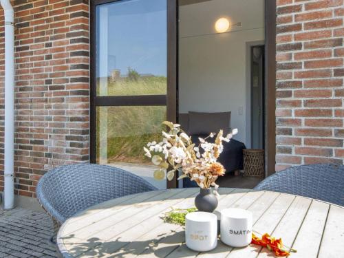 a table with a vase of flowers on a patio at Apartment in Holiday park- shared kitchen in Ulfborg