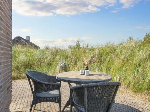 a table and chairs sitting on a patio with grass at Apartment in Holiday park- shared kitchen in Ulfborg