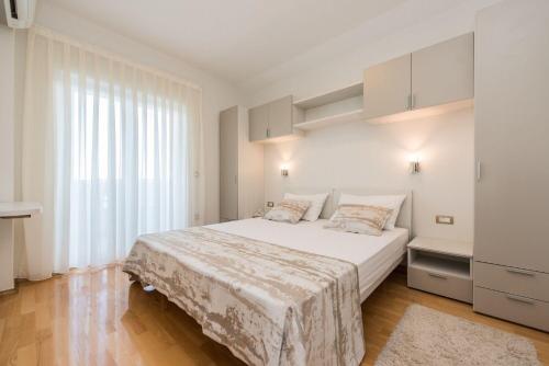Un dormitorio blanco con una cama grande y una ventana. en Apartments Tomo, en Novalja