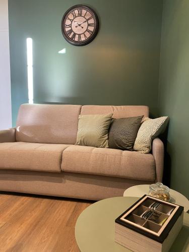 un salon avec un canapé et une horloge au mur dans l'établissement Marianne 5, à Bergerac