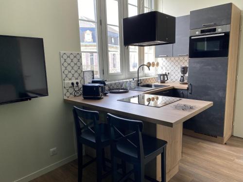 eine Küche mit einer Spüle und einer Theke mit 2 Stühlen in der Unterkunft Marianne 5 in Bergerac