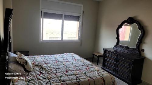a bedroom with a bed and a mirror and a dresser at résidence bouylaghman in Monte ʼArrouit