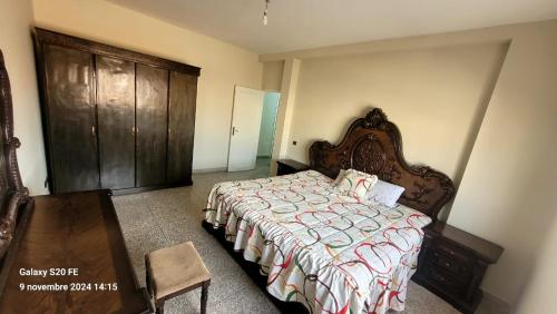 a bedroom with a bed and a wooden cabinet at résidence bouylaghman in Monte ʼArrouit