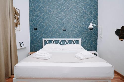 a bedroom with a white bed with blue wallpaper at Bonne Nuit Terracina in Terracina