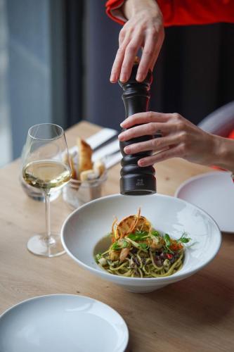 a woman is preparing a plate of pasta with a wine glass at Hotel Convictus Cracovia for business & travellers in Kraków