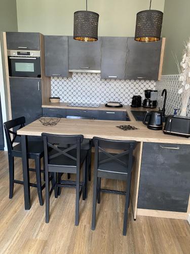 une cuisine avec une table en bois et des chaises noires dans l'établissement Marianne 7, à Bergerac