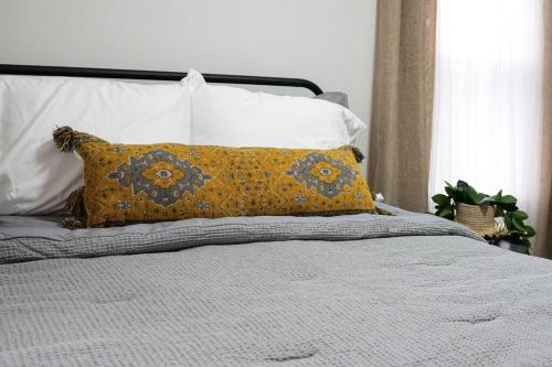 a bed with a yellow pillow on top of it at Cozy & Convenient Getaway 3BD 2BA Dog Friendly in Akron