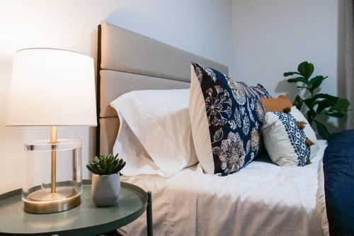 a bed with pillows and a table with a lamp at Cozy & Convenient Getaway 3BD 2BA Dog Friendly in Akron